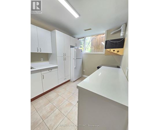 A white kitchen with a refrigerator, cabinets, and a counter.