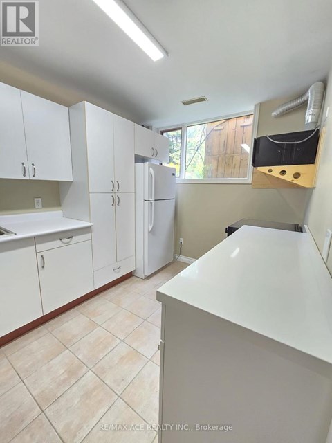 A white kitchen with a refrigerator, cabinets, and a counter.