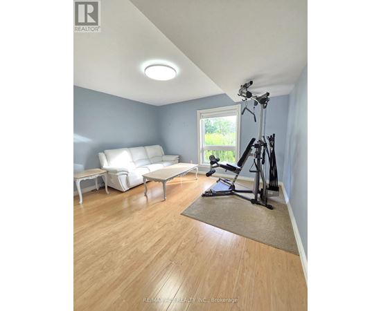 A living room with a white couch and a treadmill.
