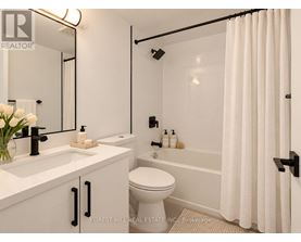A white bathroom with a toilet, sink, and shower.