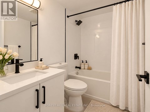 A white bathroom with a toilet, sink, and shower.