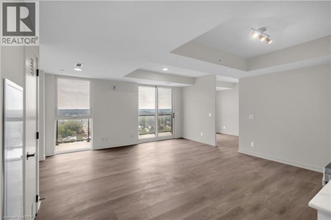 A spacious room with wooden floors and a sliding glass door leading to a balcony.
