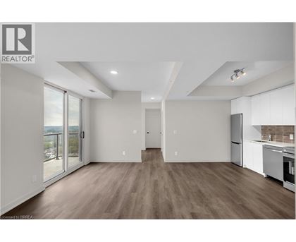 A spacious, well-lit kitchen and living room with hardwood floors and modern appliances.