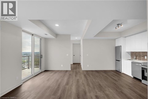 A spacious, well-lit kitchen and living room with hardwood floors and modern appliances.