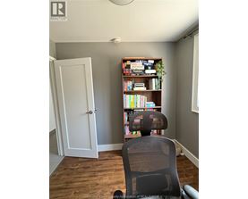 A room with a bookshelf, a chair, and a door.