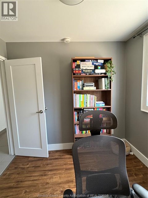 A room with a bookshelf, a chair, and a door.