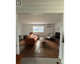 A living room with a brown couch and a white chair.