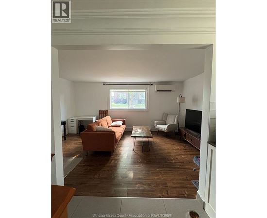 A living room with a brown couch and a white chair.