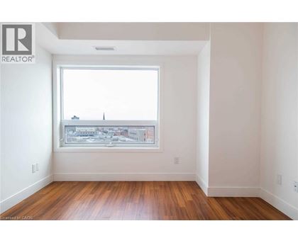 A room with a window showing a cityscape and wooden floors.