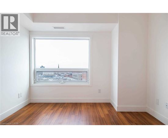 A room with a window showing a cityscape and wooden floors.