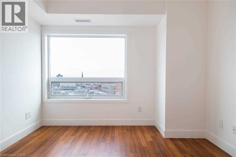 A room with a window showing a cityscape and wooden floors.