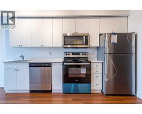 A kitchen with a stainless steel refrigerator, a black microwave, a black oven, and a black dishwasher.