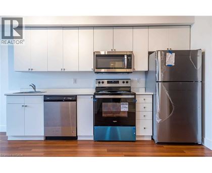 A kitchen with a stainless steel refrigerator, a black microwave, a black oven, and a black dishwasher.