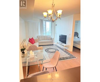 A well-lit, modern living room with a glass table and a white sofa.