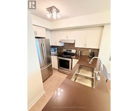 A kitchen with a refrigerator, oven, and sink.