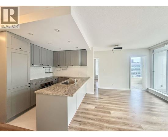 A modern kitchen with a granite countertop and stainless steel appliances.