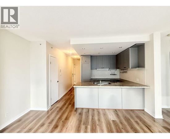 A kitchen with white cabinets and a wooden floor.