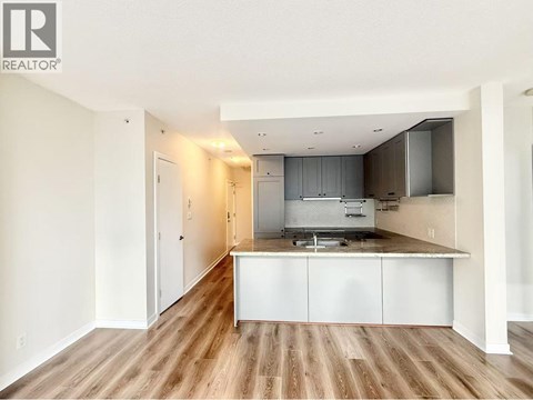 A kitchen with white cabinets and a wooden floor.