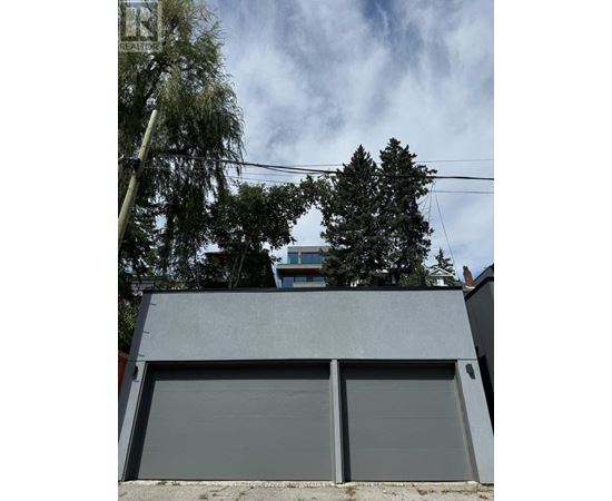 A grey garage door is closed and there is a tree in front of a building.
