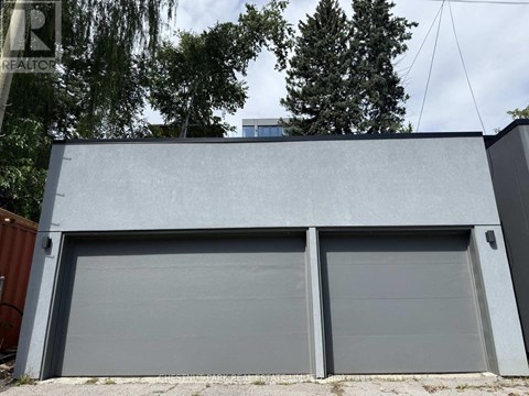 A grey garage door is closed and there is a tree in the background.