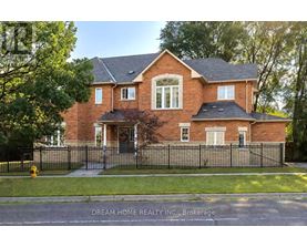A brick house with a black fence in front.