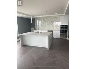A modern kitchen with a white island and wooden flooring.