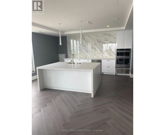 A modern kitchen with a white island and wooden flooring.