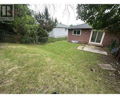 A backyard with a brown house and a green lawn.