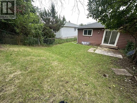 A backyard with a brown house and a green lawn.