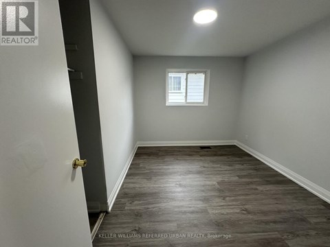 A room with a wooden floor and a window with white blinds.
