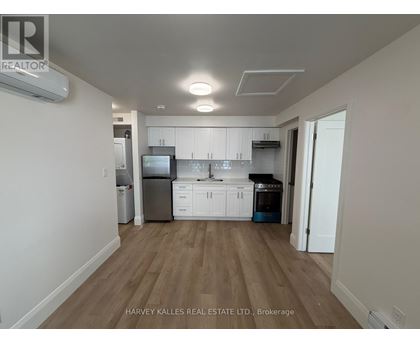 A kitchen with white cabinets and a wooden floor.