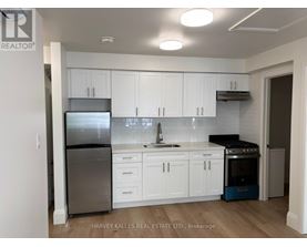 A kitchen with white cabinets and a stainless steel refrigerator.