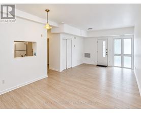 A spacious room with wooden flooring and white walls.