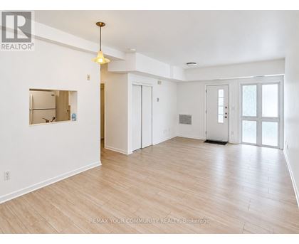A spacious room with wooden flooring and white walls.