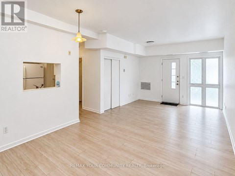 A spacious room with wooden flooring and white walls.