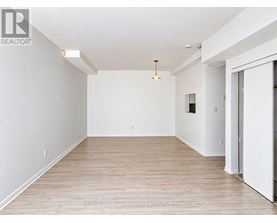 A large, empty room with wooden flooring and white walls.
