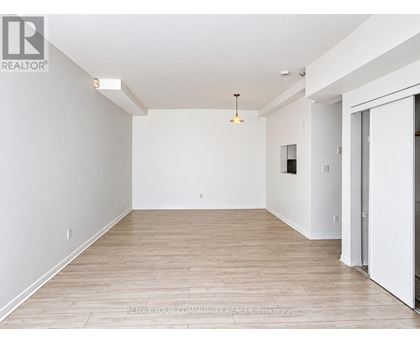 A large, empty room with wooden flooring and white walls.