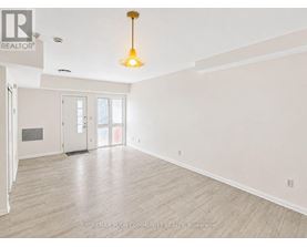 A large, empty room with a wooden floor and a hanging light fixture.