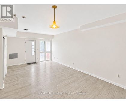 A large, empty room with a wooden floor and a hanging light fixture.
