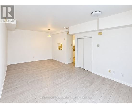 A spacious room with white walls and a wooden floor.