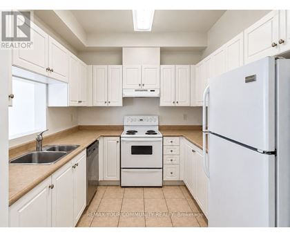A white kitchen with a refrigerator, sink, stove, and cabinets.