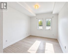 A white room with a window and wooden flooring.