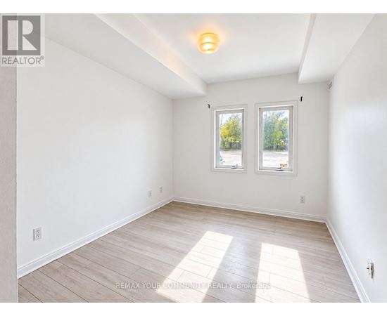 A white room with a window and wooden flooring.