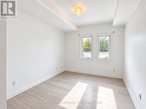 A white room with a window and wooden flooring.