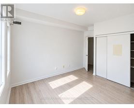 A room with white walls and wooden flooring, with a door on the right side.