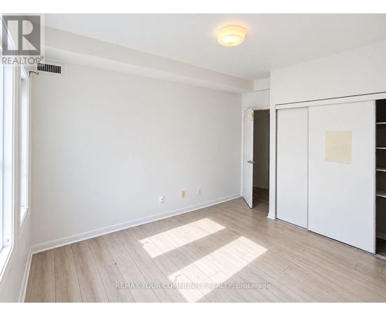 A room with white walls and wooden flooring, with a door on the right side.
