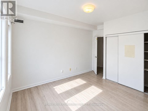 A room with white walls and wooden flooring, with a door on the right side.