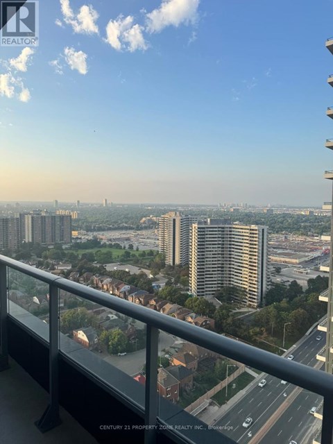 A balcony overlooks a cityscape with a highway and buildings.