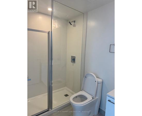 A white toilet in a bathroom with a glass shower door.