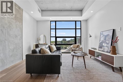 A living room with a black couch and a large window.